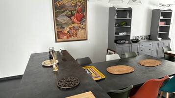 A modern kitchen with a dark countertop, wooden cutting board, and colorful chairs.