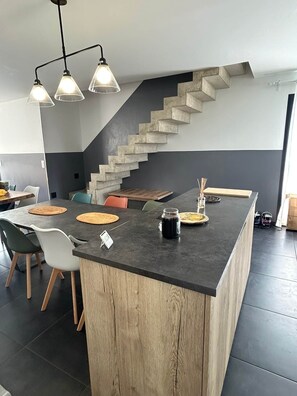 A modern kitchen with a central island, a staircase, and pendant lighting. - 5-bedroom house, overlooking the lake and near the ocean (Leucate)