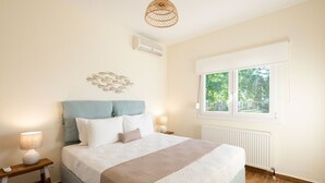 Ein Schlafzimmer mit Bett, Nachttischlampen, einem Fenster und einer Wandklimaanlage.