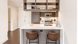 Eine moderne Küche mit Kochinsel, Barhocker, Mikrowelle und Backofen.