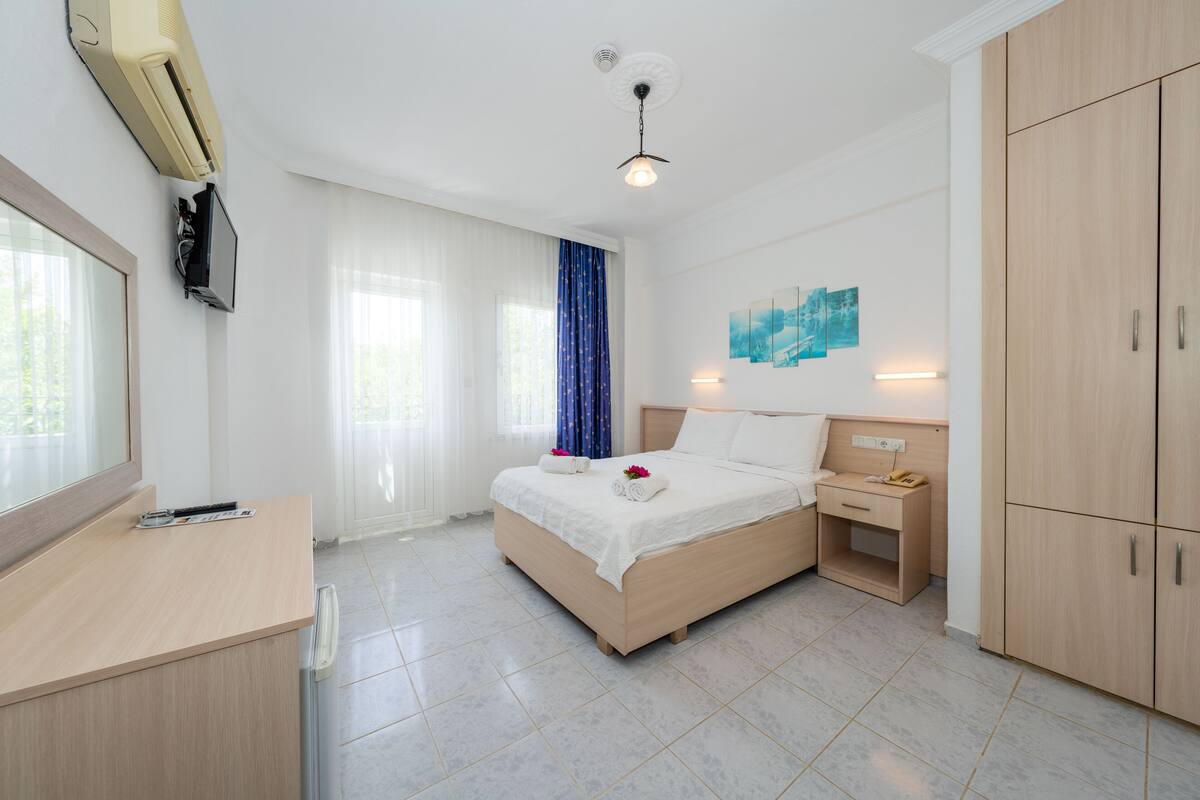Habitación de hotel con cama, mesita de noche, armario y escritorio con silla.