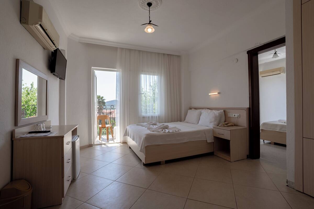 Habitación de hotel con cama, mesita de noche, televisor y vistas al exterior.