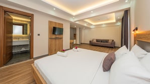 A modern hotel room with a large bed, a wooden wardrobe, a television, and a sofa. - Gokcen Hotel & Aparments (Fethiye)