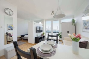 A modern living room with a dining table, chairs, a TV, and a city view through large windows. - Modern Studio in the Center | View of the City | Close to the Theatre (Warszawa)