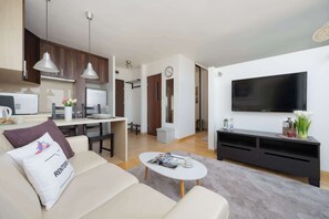 A modern living room with a sofa, coffee table, TV, and kitchen area. - Modern Studio in the Center | View of the City | Close to the Theatre (Warszawa)