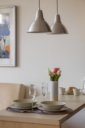A dining table with a vase of tulips, a glass, and a cup. - Modern Studio in the Center | View of the City | Close to the Theatre (Warszawa)