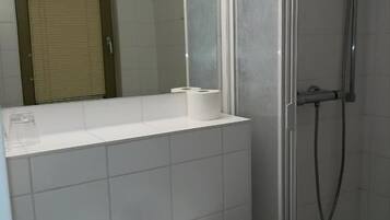 A bathroom with a sink, mirror, and shower.