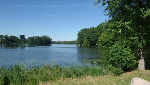 A calm lake surrounded by lush greenery and trees. - Pension am Seeberg (Zeschdorf)