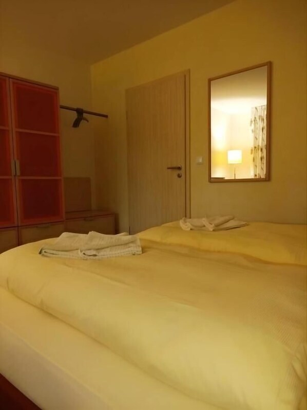 A hotel room with a bed, a wardrobe, a door, and a mirror. - Pension am Seeberg (Zeschdorf)