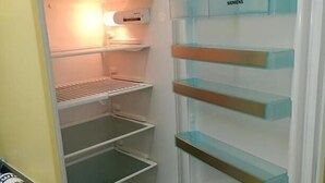 An open refrigerator with multiple shelves and a control panel. - Pension am Seeberg (Zeschdorf)