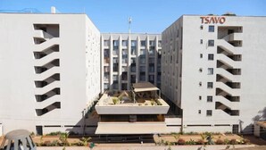Um edifício moderno com um pátio central, várias varandas e uma placa com a inscrição 'TSAVO'.