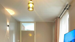 Uma sala de estar com sofá, poltrona, televisão e escrivaninha.