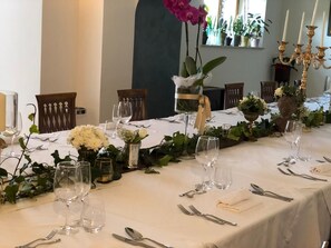 Une table à manger dressée avec de la verrerie, des couverts et des compositions florales.