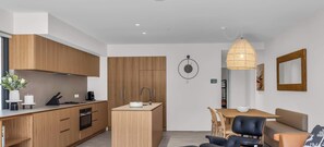 Eine moderne Küche mit Holzausstattung, einer zentralen Kochinsel und einem Essbereich mit Tisch und Stühlen.