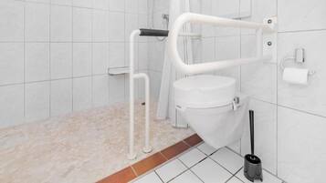 A modern bathroom with a white toilet, a shower area, and a grab bar.