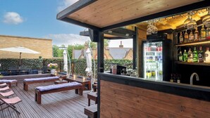 A wooden deck with lounge chairs and a bar area with a refrigerator and shelves of bottles. - En-Suite City View Room Near Brick Lane Shoreditch - Near Tower Bridge, London (London)