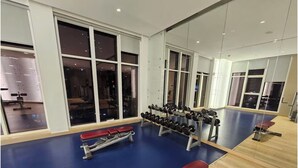 Un gimnàs amb equipament esportiu, bancs i grans finestres.