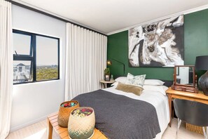 Ein modernes Schlafzimmer mit einem großen Bett, Blick auf die Stadt und einer grünen Akzentwand.