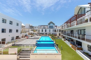 Ein modernes Hotel mit Dachpool, mehreren Balkonen und blauem Himmel.