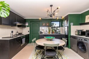 Una cocina compacta con una isla central, lavadora y comedor con mesa y sillas.