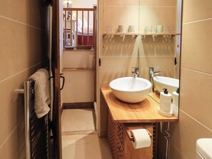 A bathroom with a wooden vanity, a large mirror, a white sink, and a toilet. - Beckside Studio (Penrith)