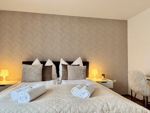Ein Hotelzimmer mit einem Bett, zwei Nachttischlampen, einem Sessel und einem Nachttisch mit einer Pflanze.