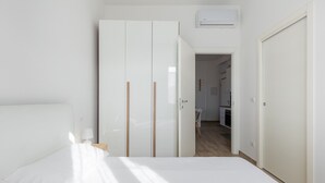 Un dormitorio con una cama, un armario y una puerta abierta que da a una zona de cocina.