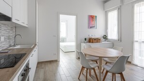 Una cocina moderna con armarios blancos, encimera de madera y horno empotrado.