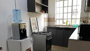 A kitchen with a refrigerator, stove, and water dispenser. - Snowhaven Kitengela| Modern, Secure Stay near Town (Kitengela)