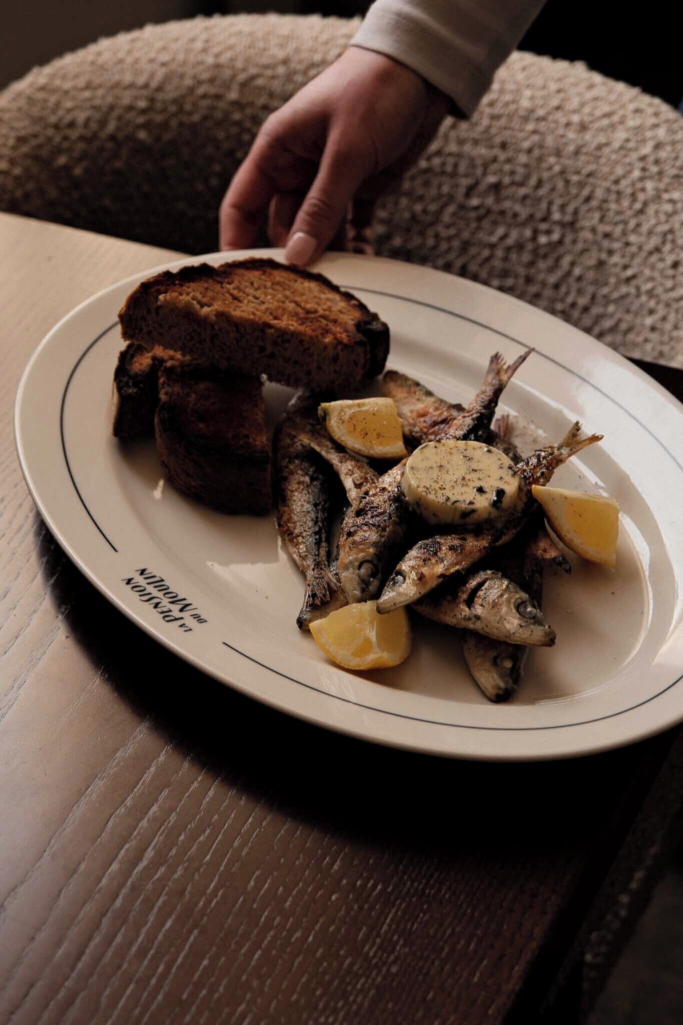 Ein Teller gegrillter Fisch und Brot auf einem Tisch.