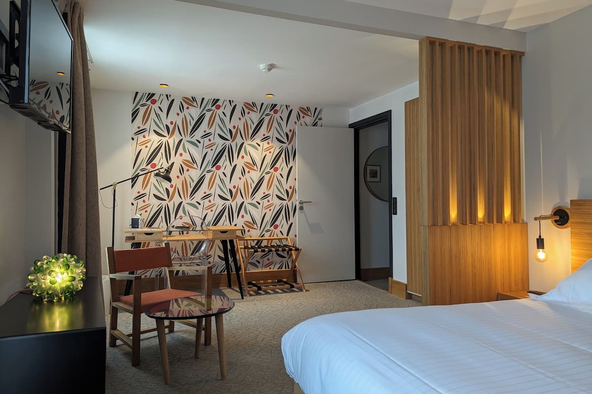 Een hotelkamer met een bed, een bureau, een stoel, een decoratieve wand en een houten paneel.