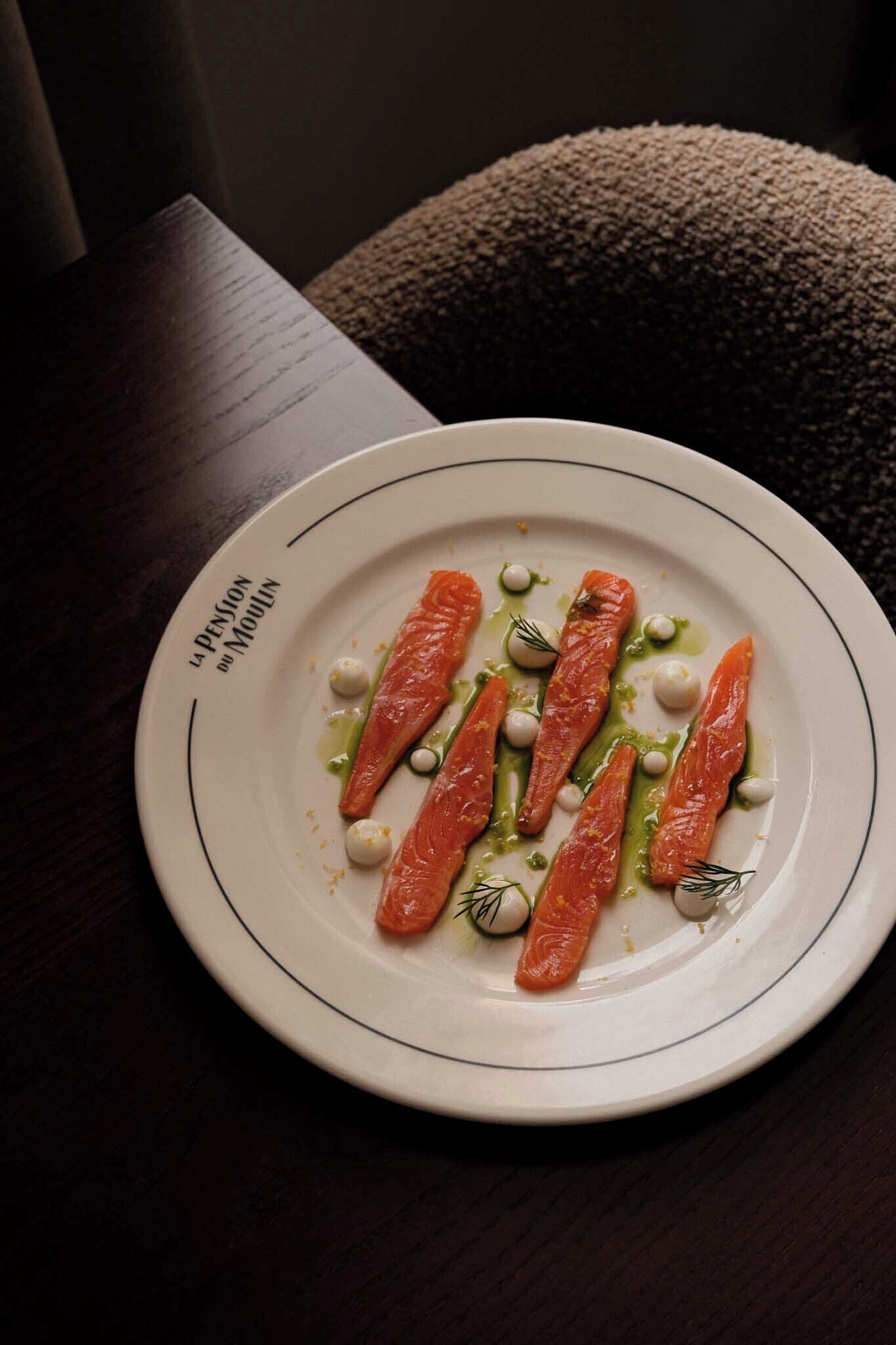 Un plato de comida con salmón y guarniciones sobre una mesa.