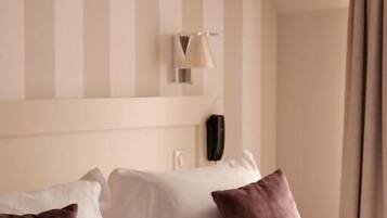 A hotel room with a bed, striped walls, a lamp, and a window with curtains.