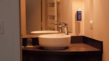 A bathroom with a white sink, a mirror, and a Phytomen brand bottle.