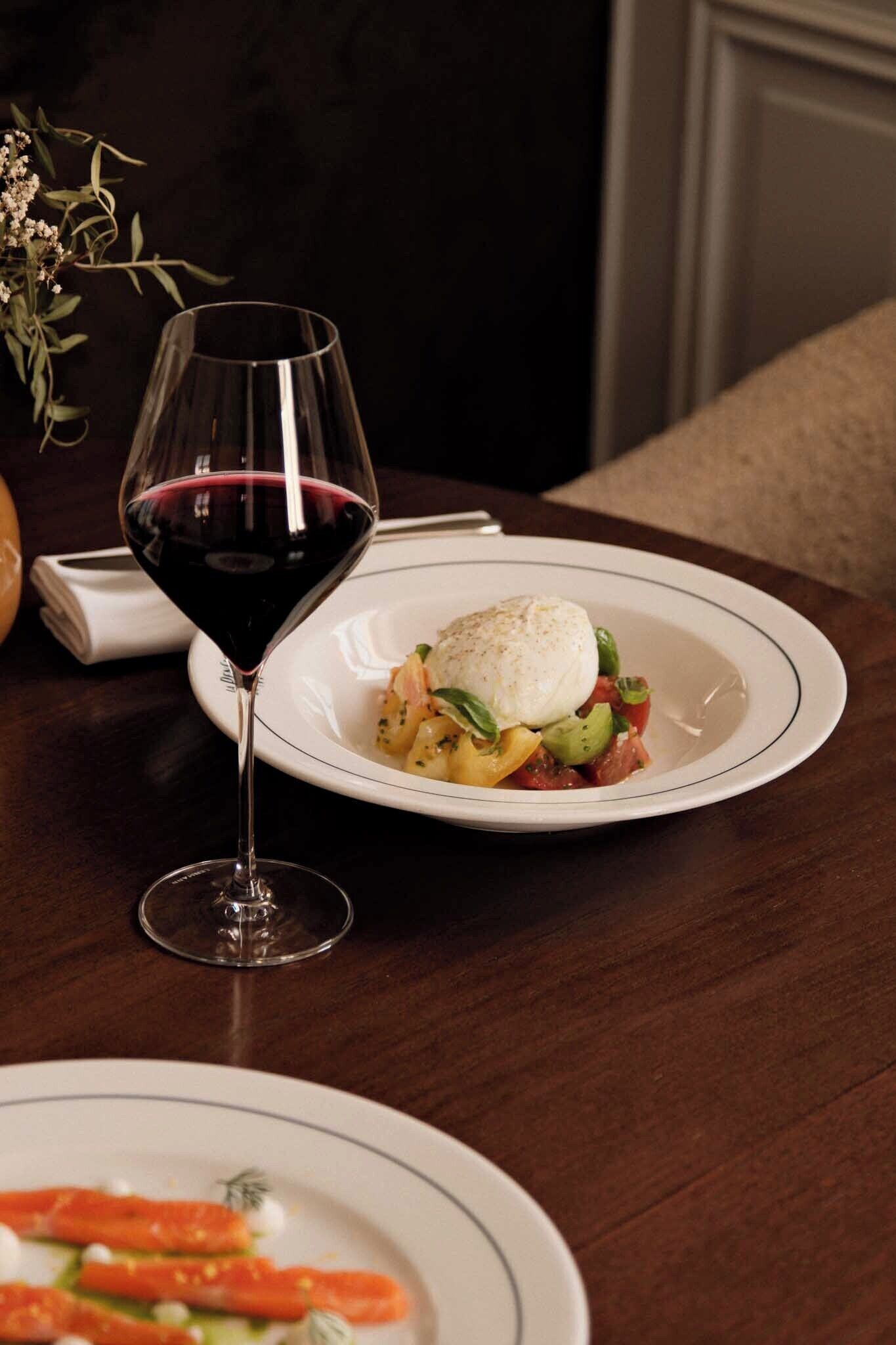 Una mesa de comedor con un plato de comida y una copa de vino.
