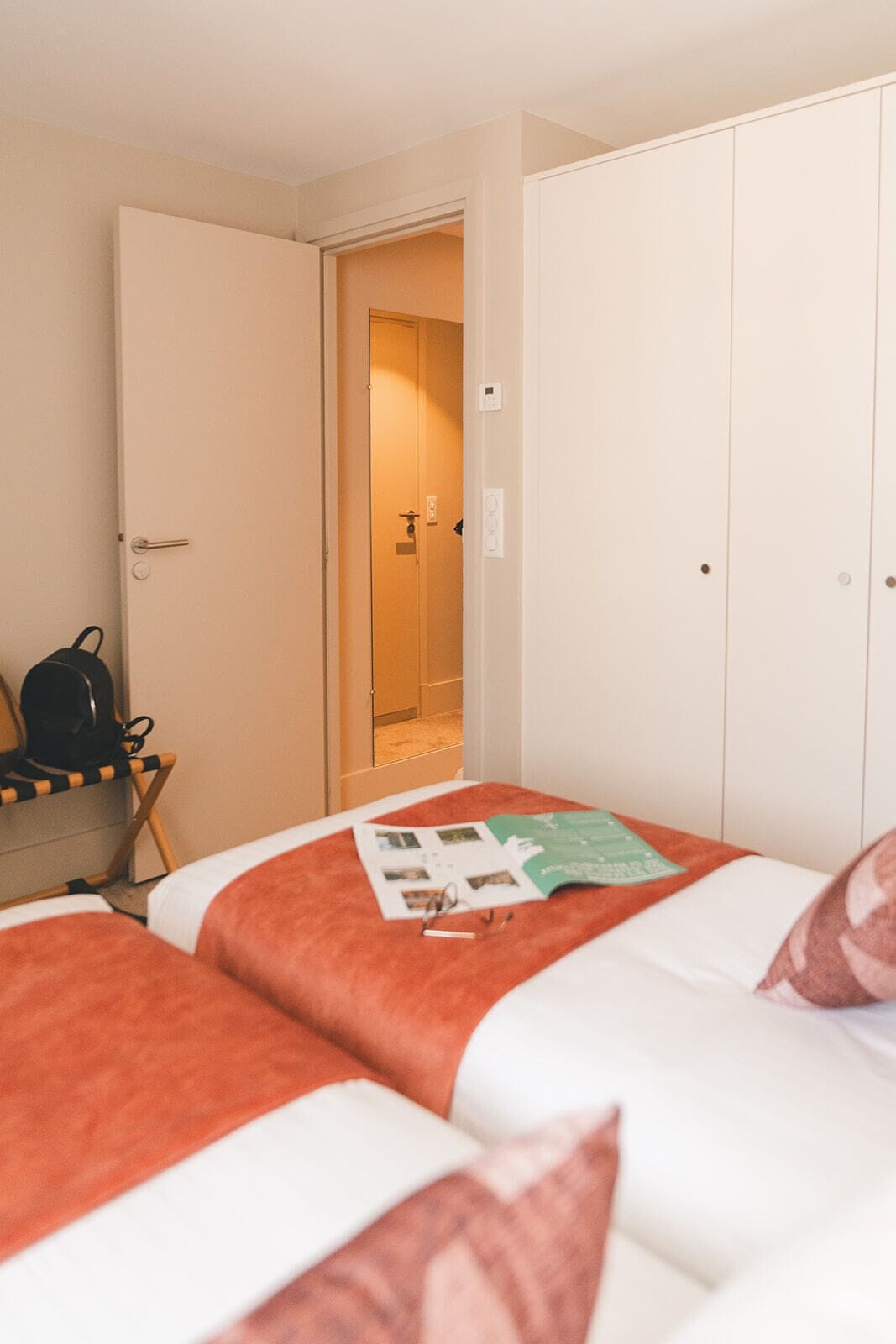 A hotel room with a bed, a chair, a desk, and a wardrobe.