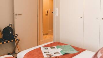 A hotel room with a bed, a chair, a desk, and a wardrobe.
