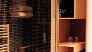 Een kamer met een glazen wand, houten planken, een handdoekhouder en een kleine prullenbak.