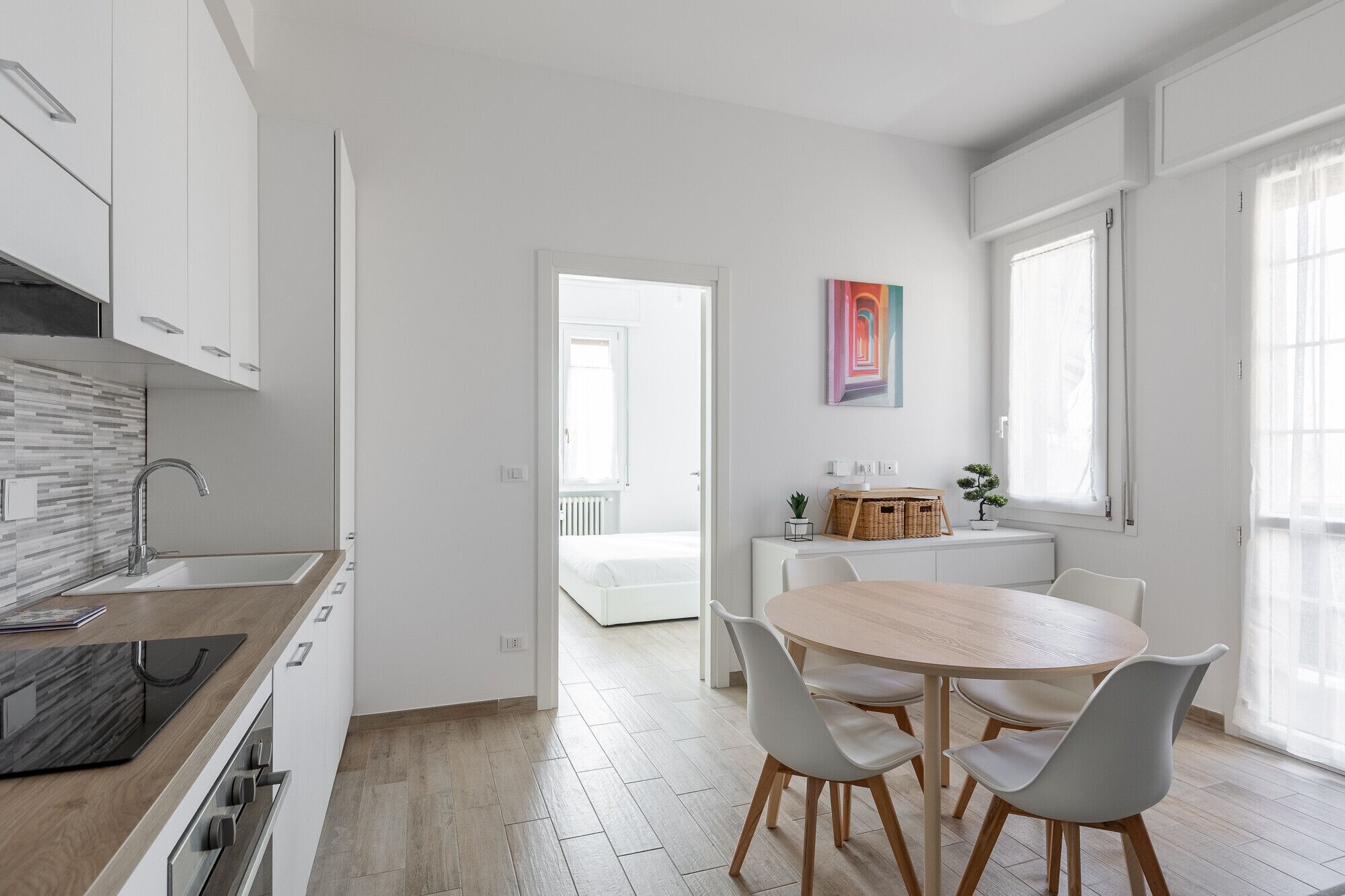 Une cuisine moderne avec des armoires blanches, un plan de travail en bois et un four encastré.