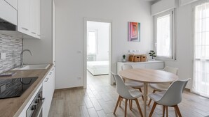 A modern kitchen with white cabinets, a wooden countertop, and a built-in oven. - Menganti White Apartment by Wonderful Italy (Bologna)