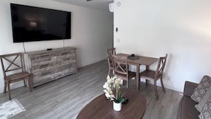 Un salon moderne doté d’un téléviseur à écran plat, de meubles en bois et d’un ventilateur de plafond.