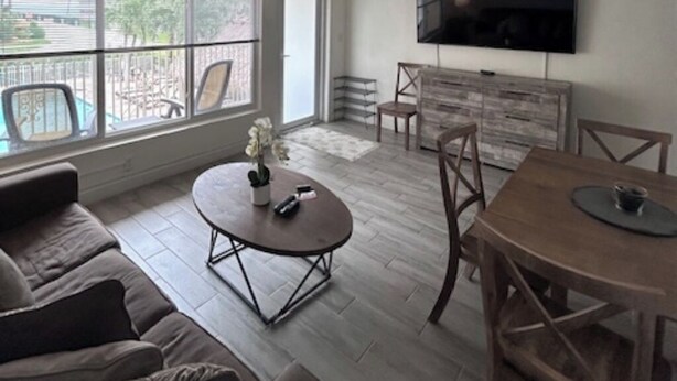 Un salon comprenant un canapé, une table basse, une table à manger, des chaises, un téléviseur et un ventilateur de plafond.