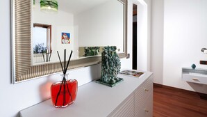A modern bathroom with a large mirror, a white vanity, a decorative vase, and a framed picture on the wall. - Estate4home - Casa Marelia (Sorrento)