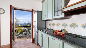 A kitchen with a view to a balcony, a refrigerator, and a tiled backsplash. - Estate4home - Casa Marelia (Sorrento)