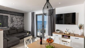 En moderne stue med sofa, spisebord og fjernsyn.