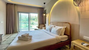 A hotel room with a large bed, a wooden headboard, a nightstand, and a view of greenery through the window. - 2 BHK/3 BED Luxury Private Pool Villa with view (Siolim)