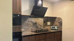 A kitchen with built-in appliances, a marble backsplash, and wooden cabinetry. - 2 BHK/3 BED Luxury Private Pool Villa with view (Siolim)