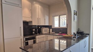 Una cucina moderna con mobili bianchi, un piano di lavoro in granito e una finestra che offre luce naturale.