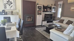 Un soggiorno moderno con camino, televisione, divano e zona pranzo con sedie e tavolo.