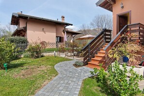A house with a paved pathway, a staircase, and a fenced garden area.